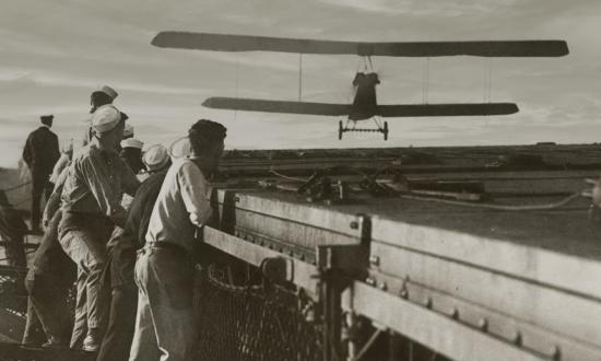 USS Langley sailors look on, an Aeromarine 39-B approaches the carrier’s flying deck